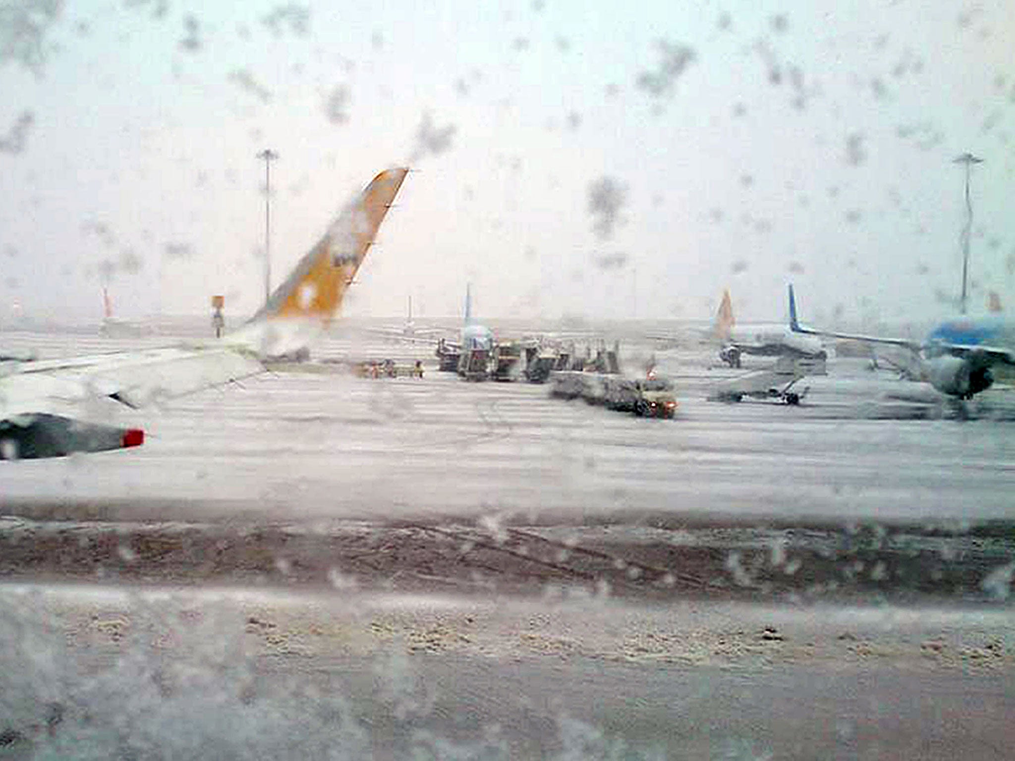 Picture of snow taken through a window of a plane stuck at Manchester Airport