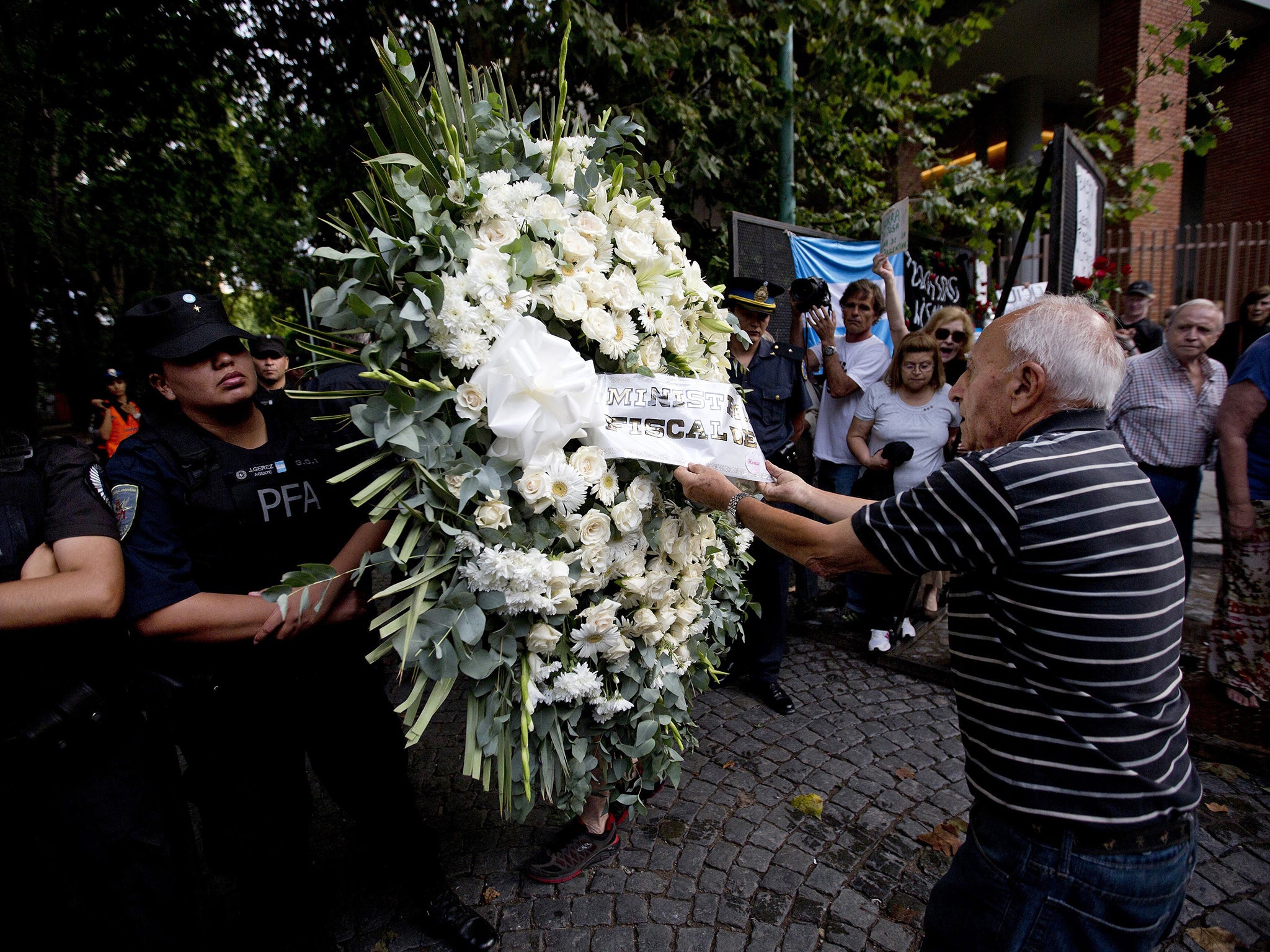 A protester pulls the ribbon from a wreath sent by the Attorney General to mark Alberto Nisman’s funeral in Buenos Aires, Argentina