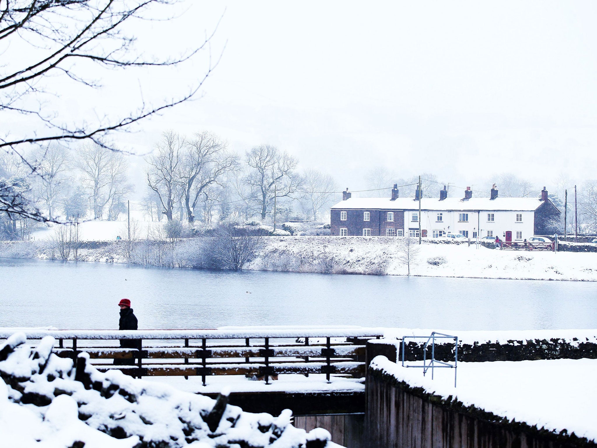 A woman walks over the bridge covered in snow, in Langley