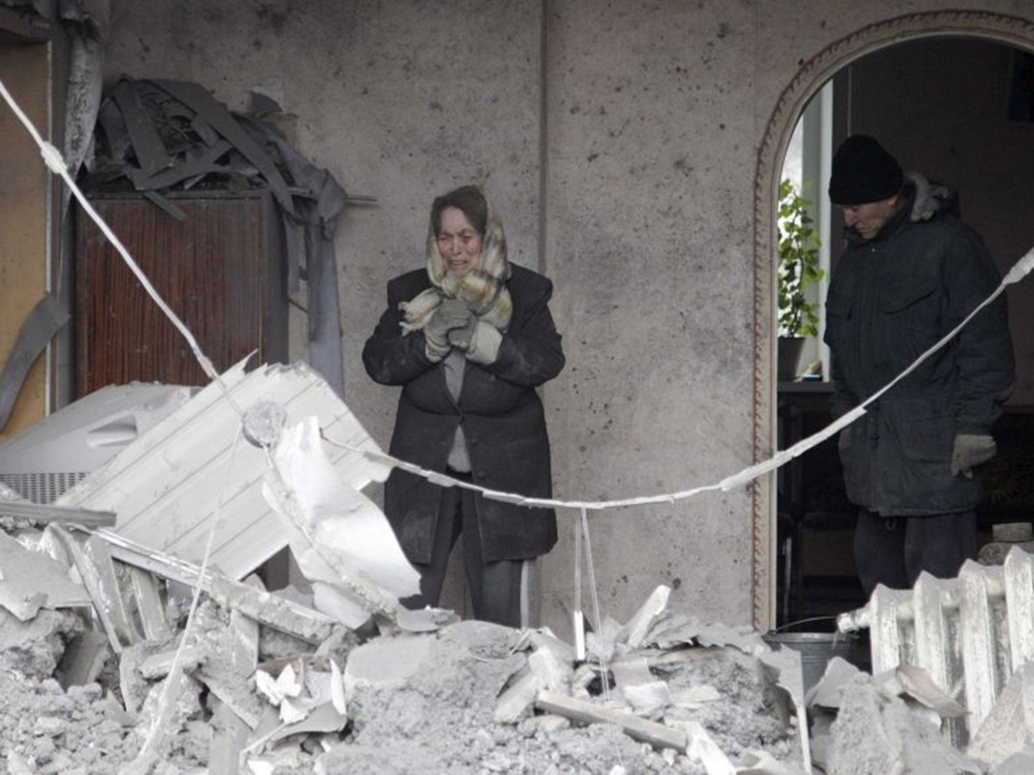 A woman reacts as she looks at the debris of her house, which according to locals was recently damaged by shelling, in the suburbs of Donetsk on 30 January