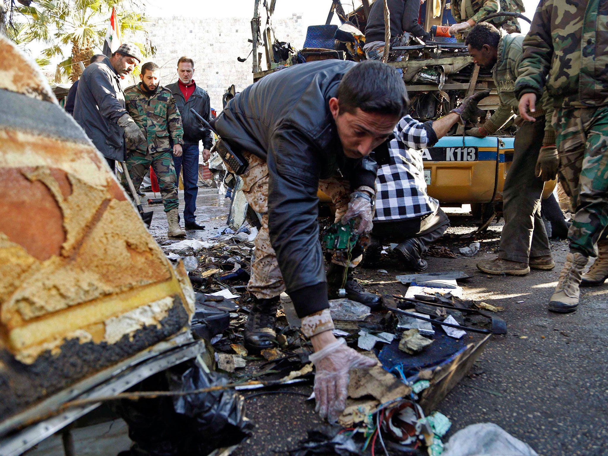 A Syrian soldier gathers evidence after an explosion occurred on a bus in central Damascus