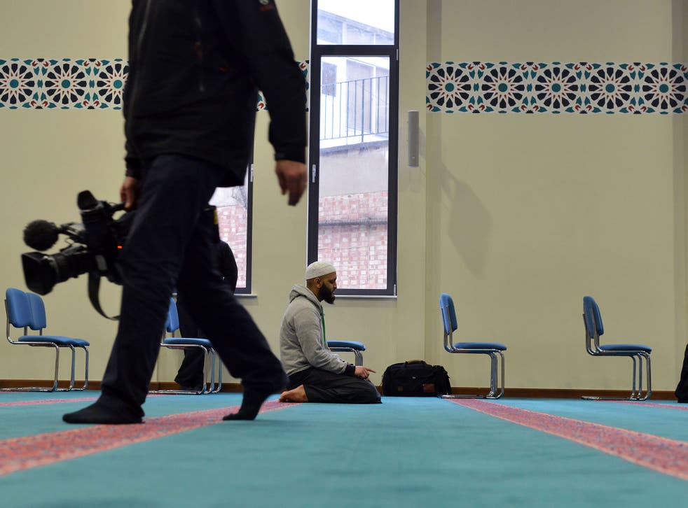 A cameraman walks past worshippers at the East London Mosque in Whitechapel yesterday. The mosque was one of 20 across the country participating in ‘Visit My Mosque Day’