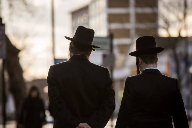 Jewish men walk along the street in Stamford Hill 