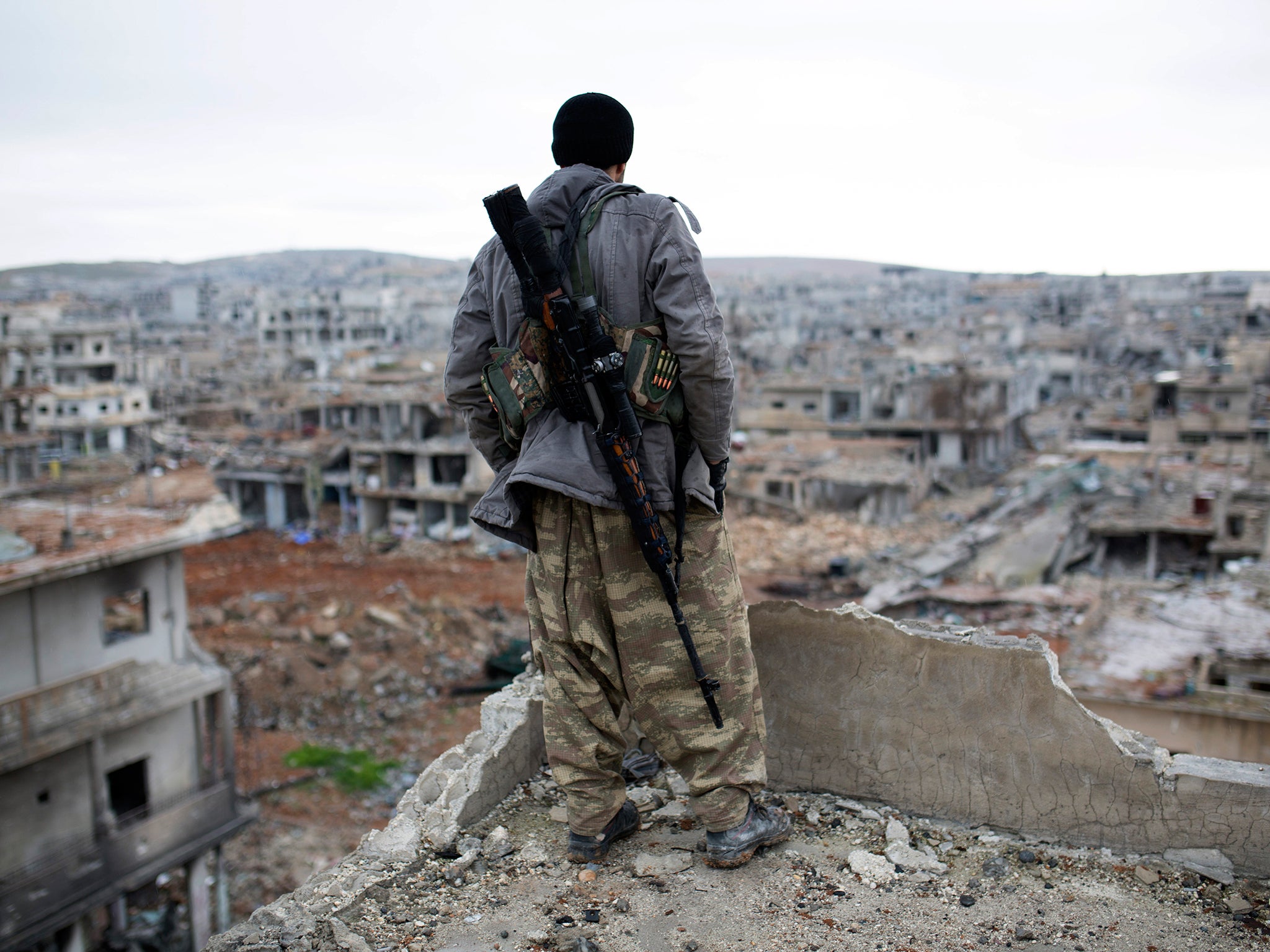 A fighter looking over the devastation of Kobani