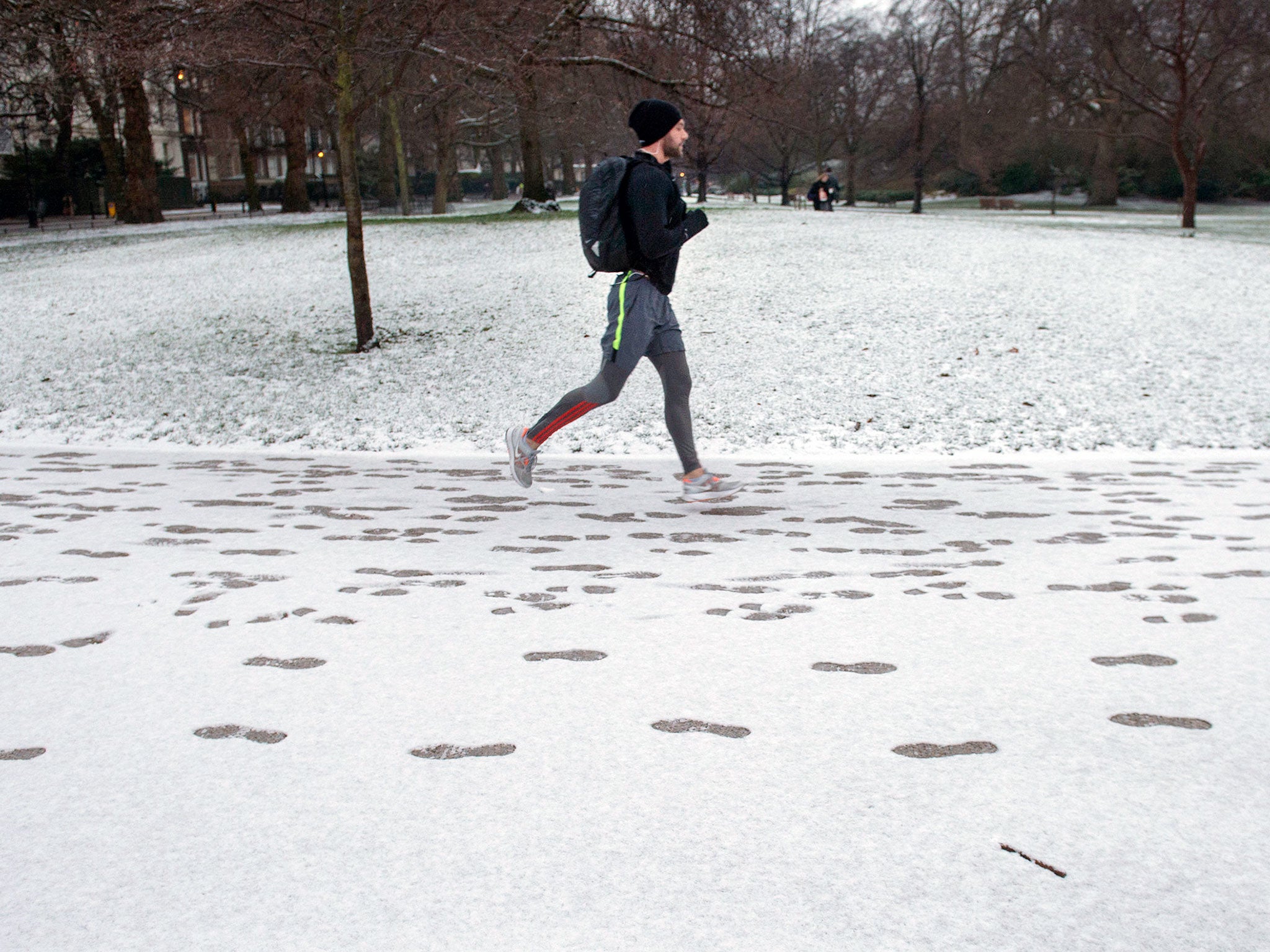 A man jogs through light snow in St James' Park, London