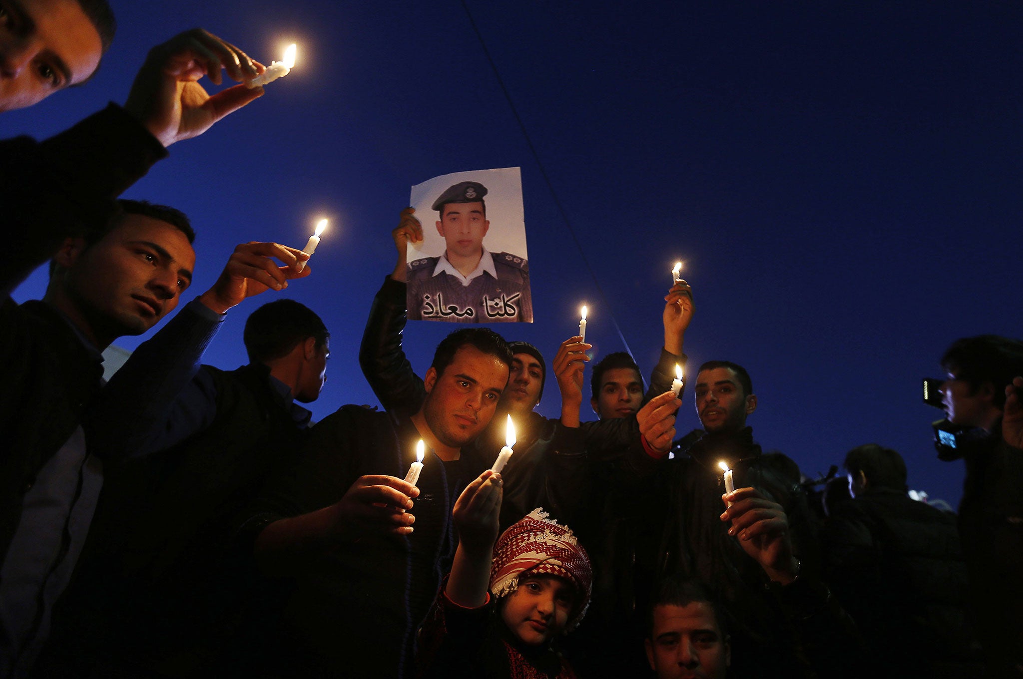 Jordanians hold up a poster of pilot Muath al-Kasaesbeh during a candlelit vigil