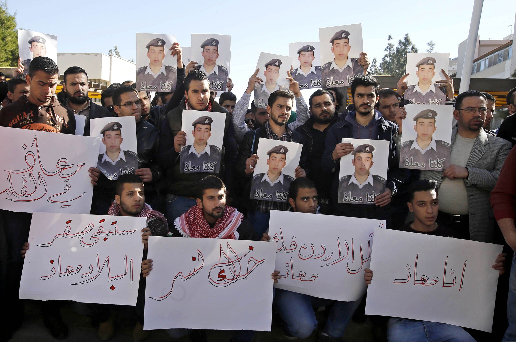 Supporters of Jordanian pilot Lt. Muath al-Kaseasbeh hold posters of him with Arabic that reads: 'We are all Muath' during a protest in Amman, Jordan