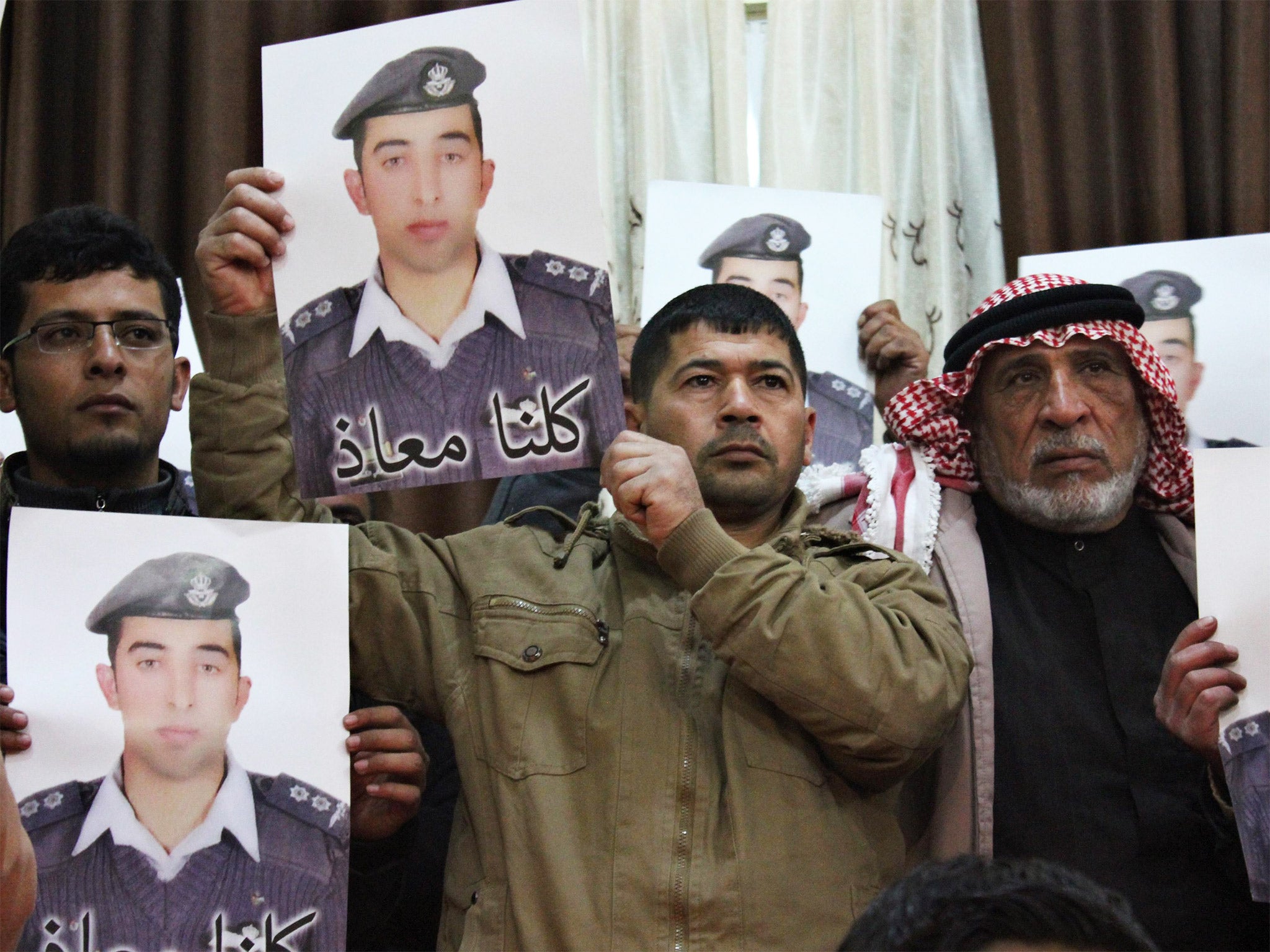 Relatives of Jordanian pilot Moazal al-Kasaesbeh hold his poster as they take part in a rally in his support at the family's headquarters in the city of Karak, last week