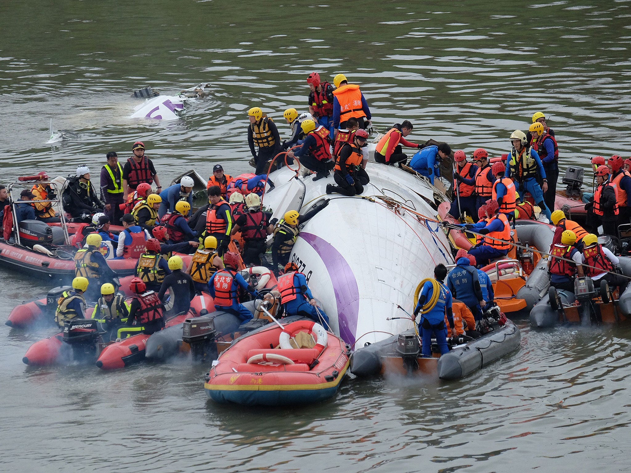 Rescue personnel work to free passengers from a TransAsia ATR 72-600 turboprop plane that crash-landed into a river outside Taiwan's capital Taipei