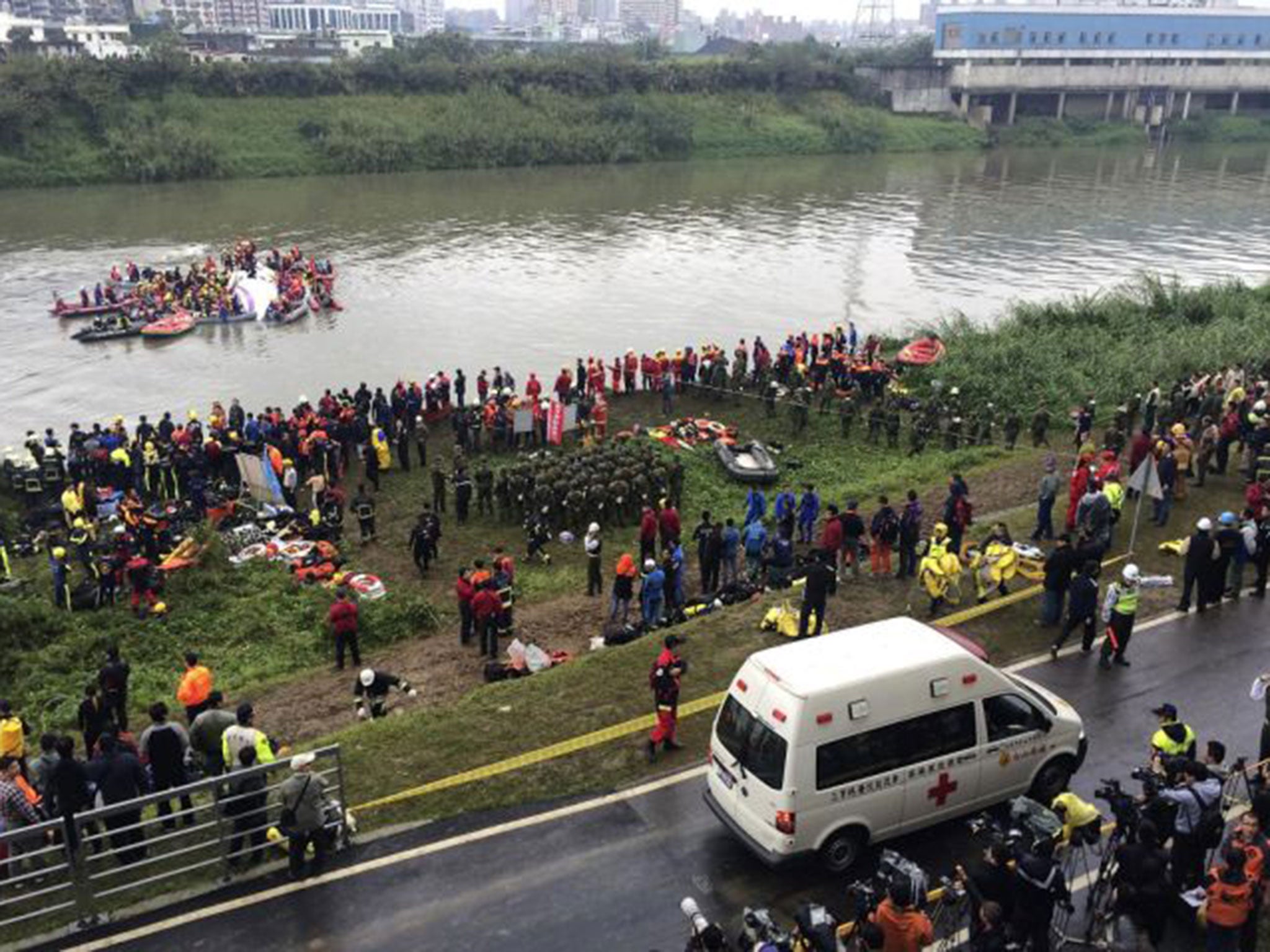 An ambulance arrives as rescuers carry out rescue operations after a TransAsia plane crashed into a river in New Taipei City,