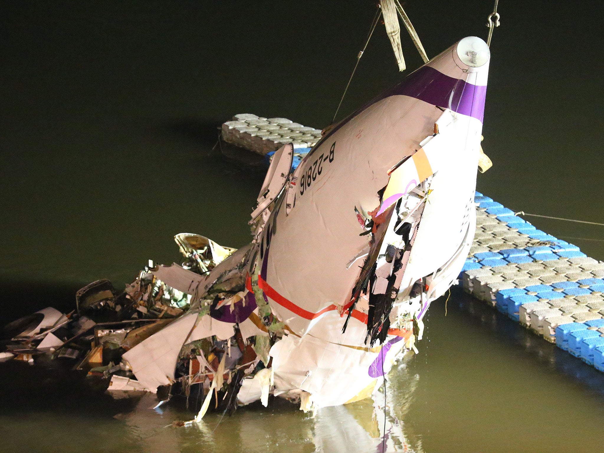 The mangled fuselage of a TransAsia Airways commercial plane is dragged to the river bank after it crashed in Taipei, Taiwan