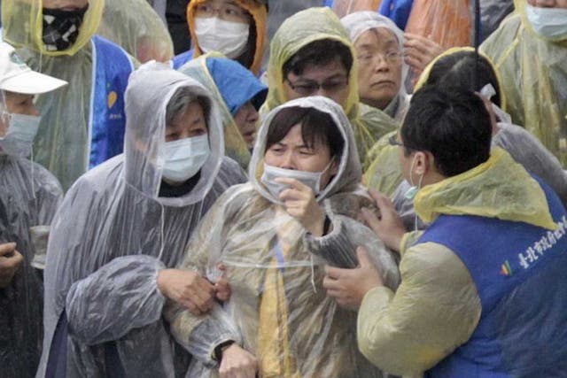 Relatives watch divers recover bodies at the Taipei crash site yesterday