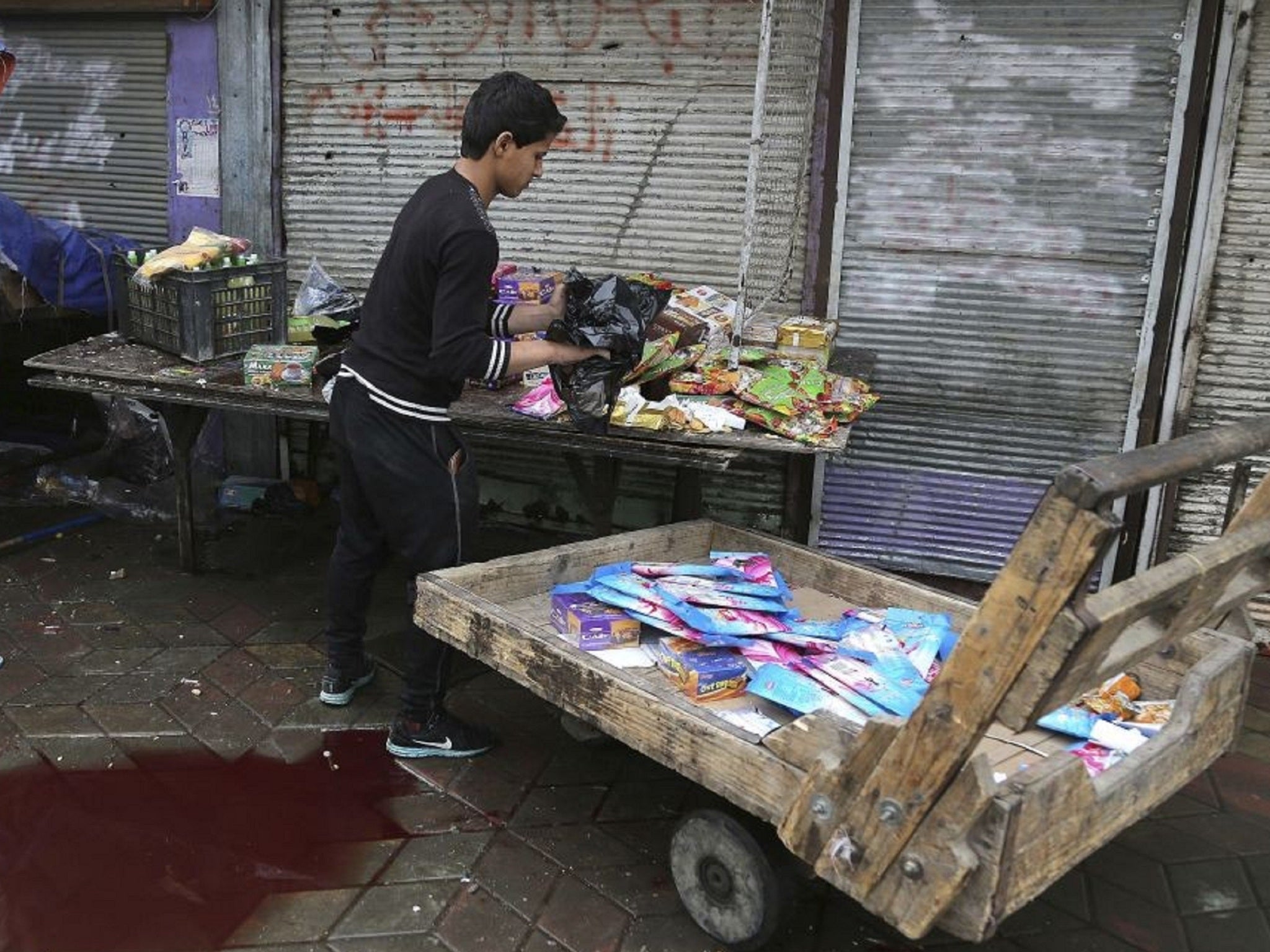 A young man clears away stock near a pool of blood