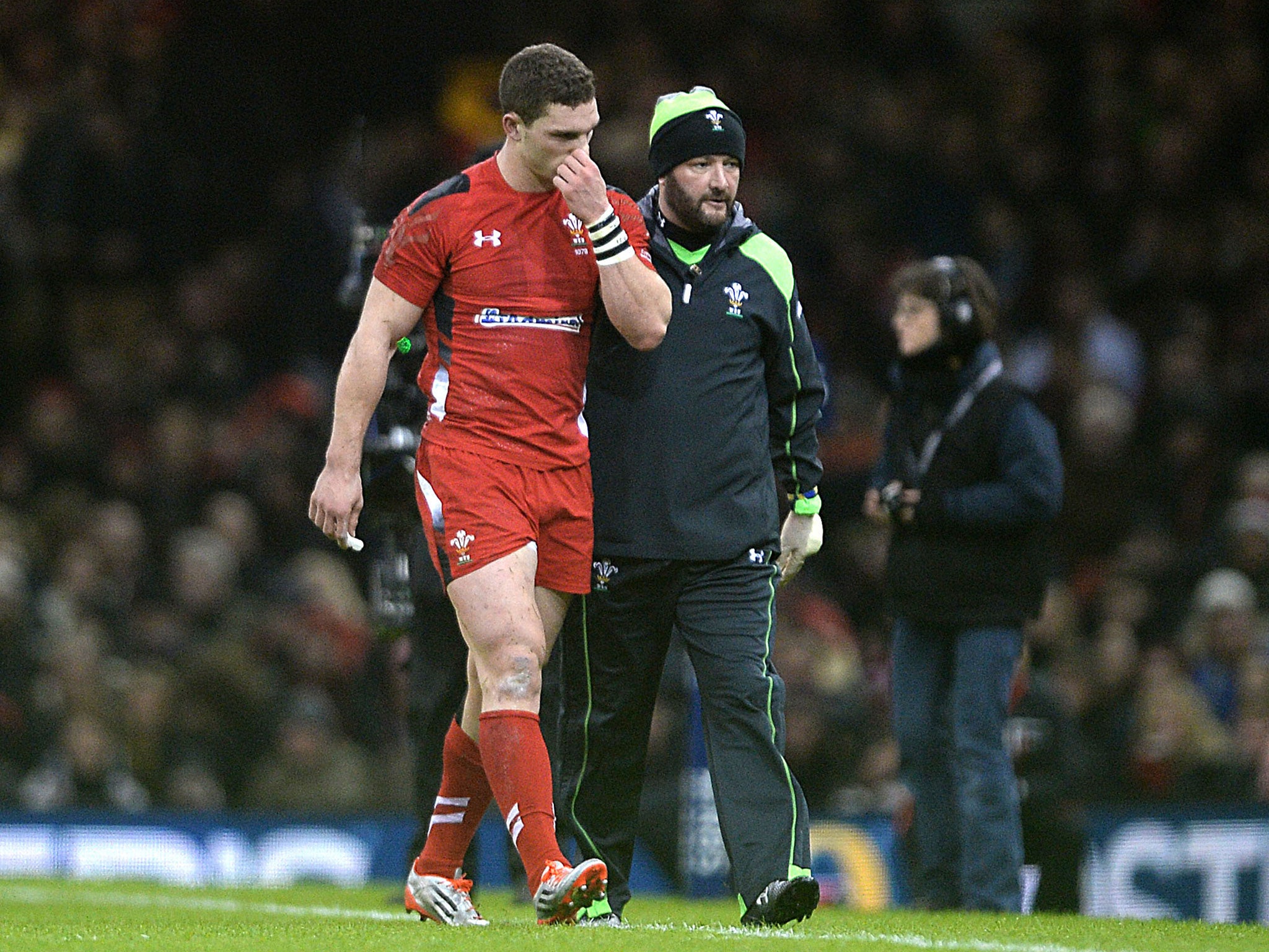 George North leaves the pitch with the Wales team doctor, Geoff Davies