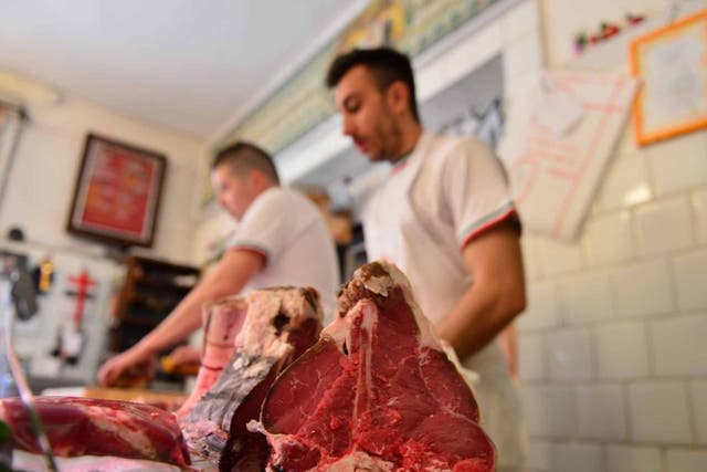 A butcher prepares his cuts at a meat shop in Italy