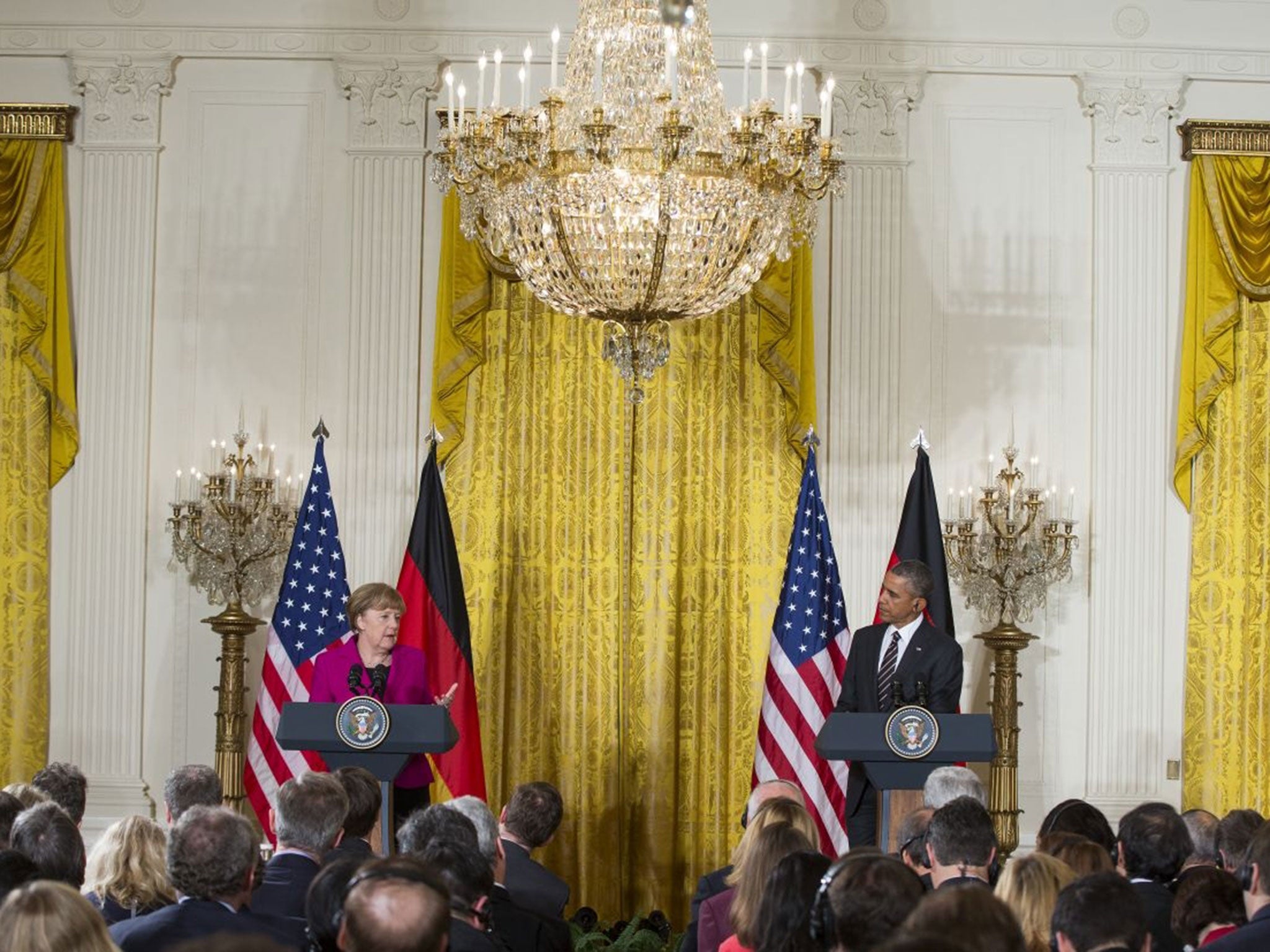 President Barack Obama listen as German Chancellor Angela Merkel speaks during their joint news conference in the East Room of the White House in Washington