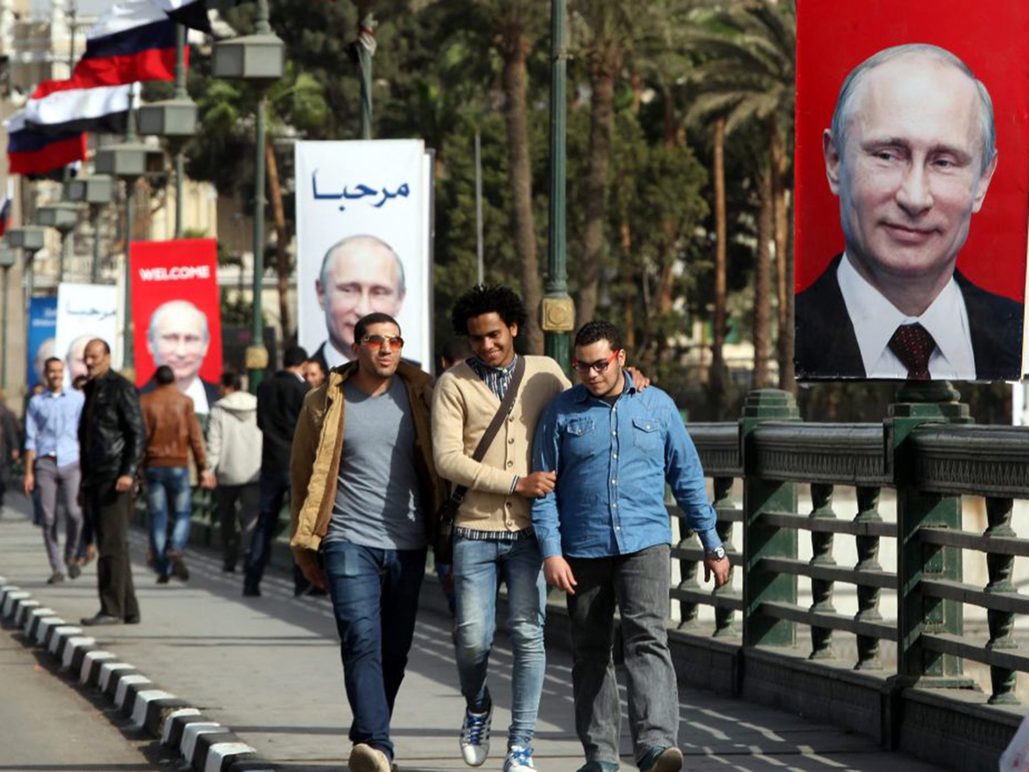 Egyptians walk past posters celebrating the arrival in Cairo yesterday of Vladimir Putin for a two-day official visit