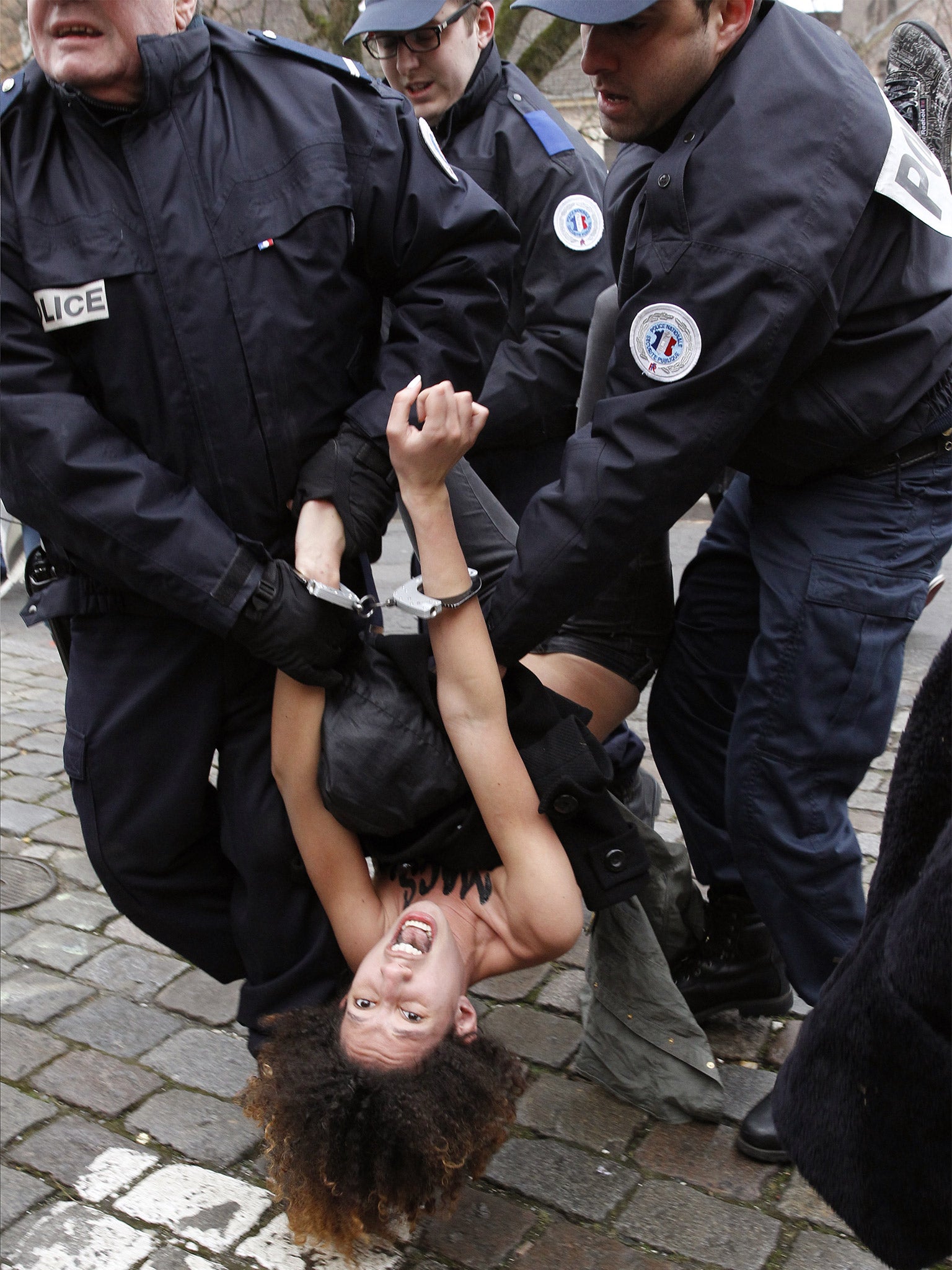 A Femen protester is carried away by police