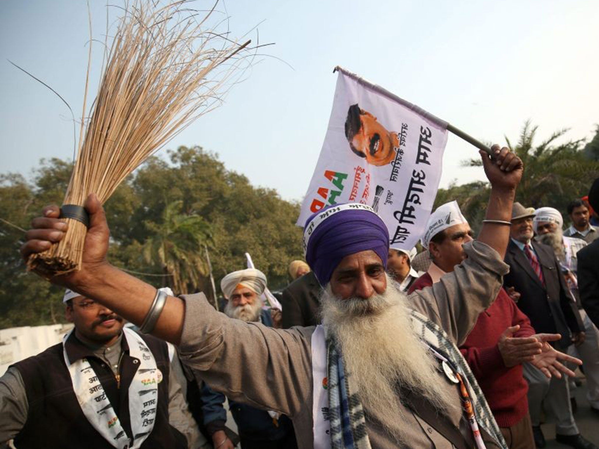 An AAP supporter waves a broom while celebrating its landslide win in Delhi Legislative Assembly elections, in Amritsar, India, on 10 February