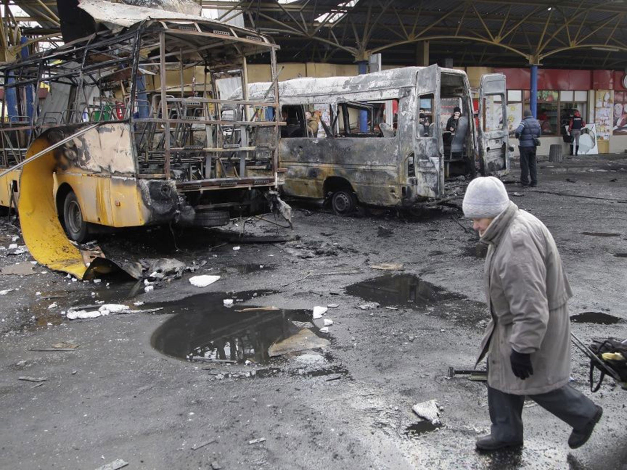 A local man walks past buses hit by shelling at a bus station in Donetsk, Ukraine, 11 February