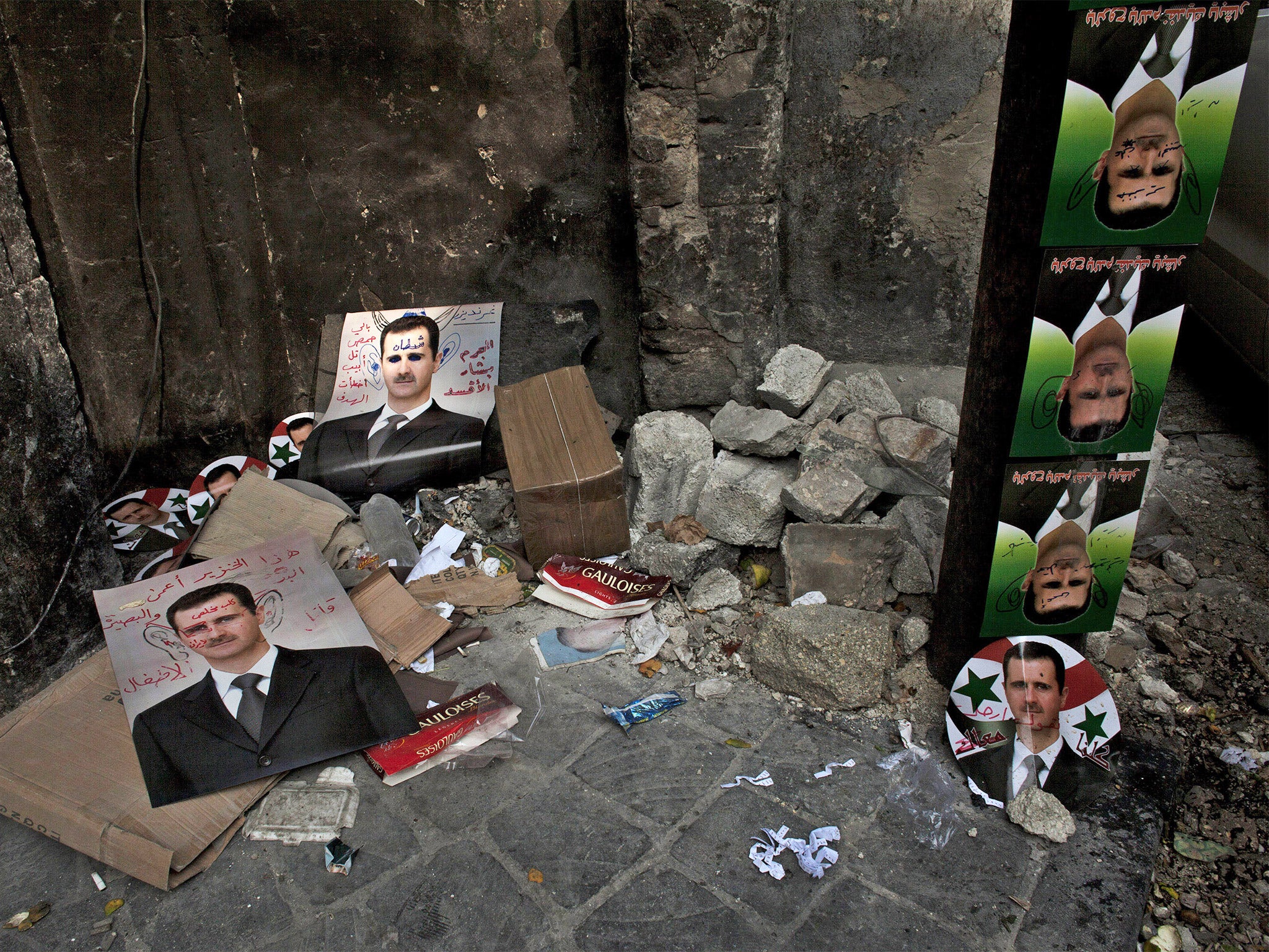 Hated: defaced posters of Bashar al-Assad in Aleppo (Getty)