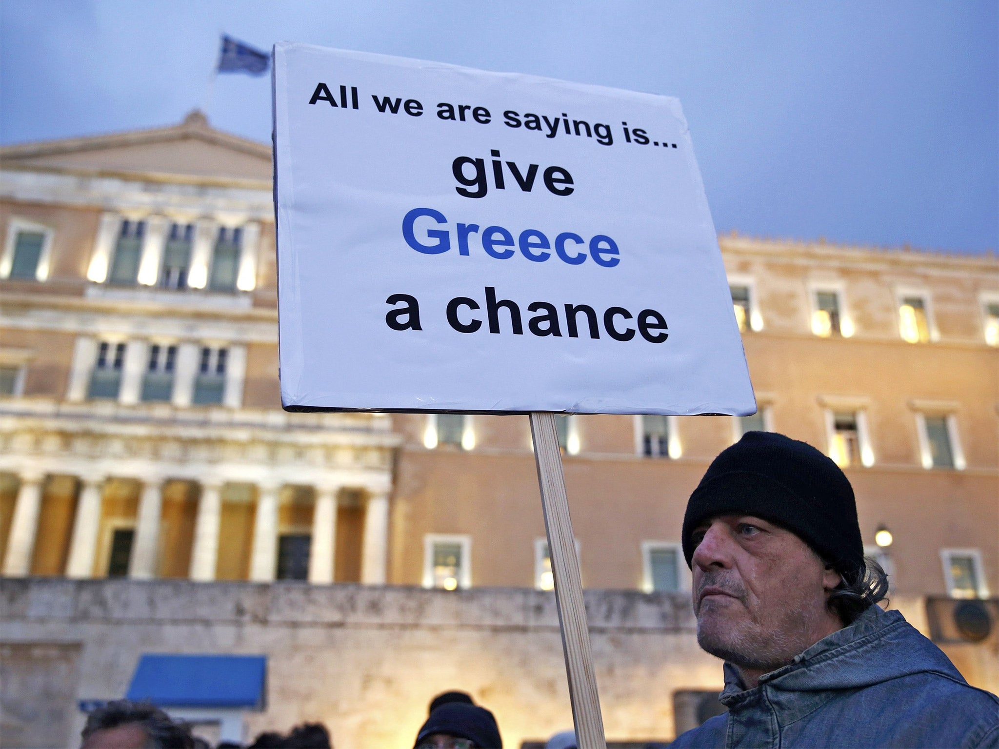 A protester displays his sign during an anti-austerity, pro-government demonstration outside the Greek parliament in Athens on Wednesday