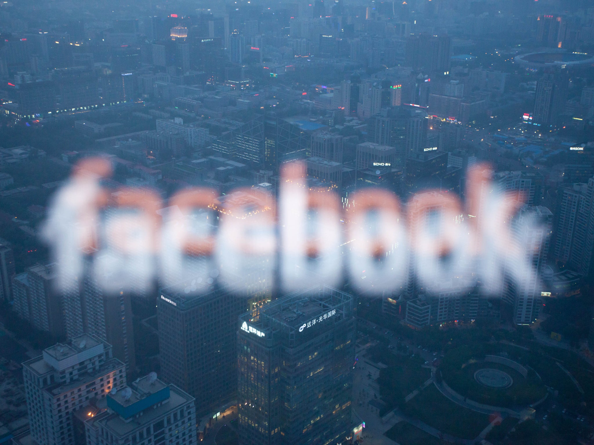 A photo taken on May 16, 2012 shows a computer screen displaying the logo of social networking site Facebook reflected in a window before the Beijing skyline