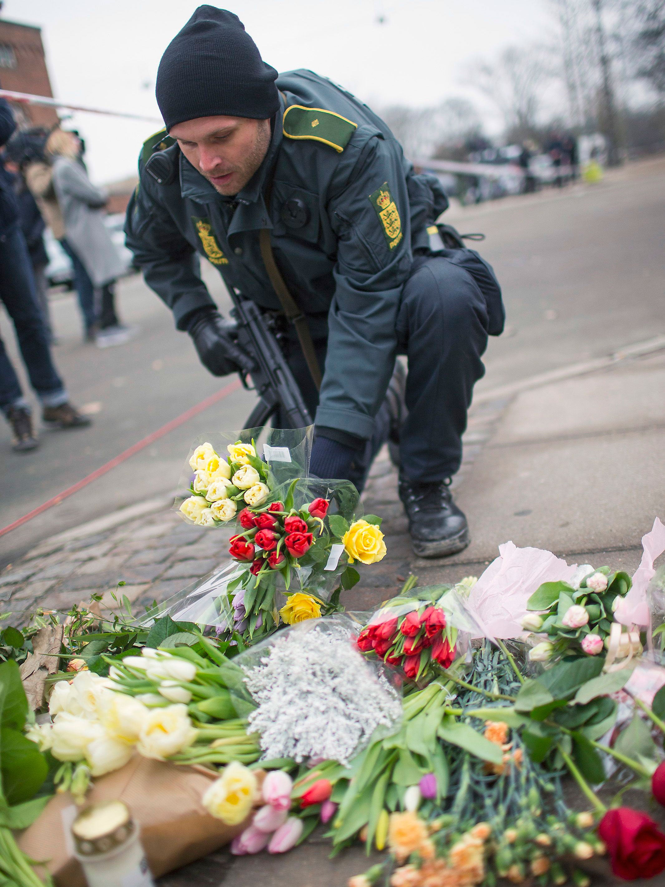 A policeman places flowers close to the scene of the cafe shooting in Oesterbroin