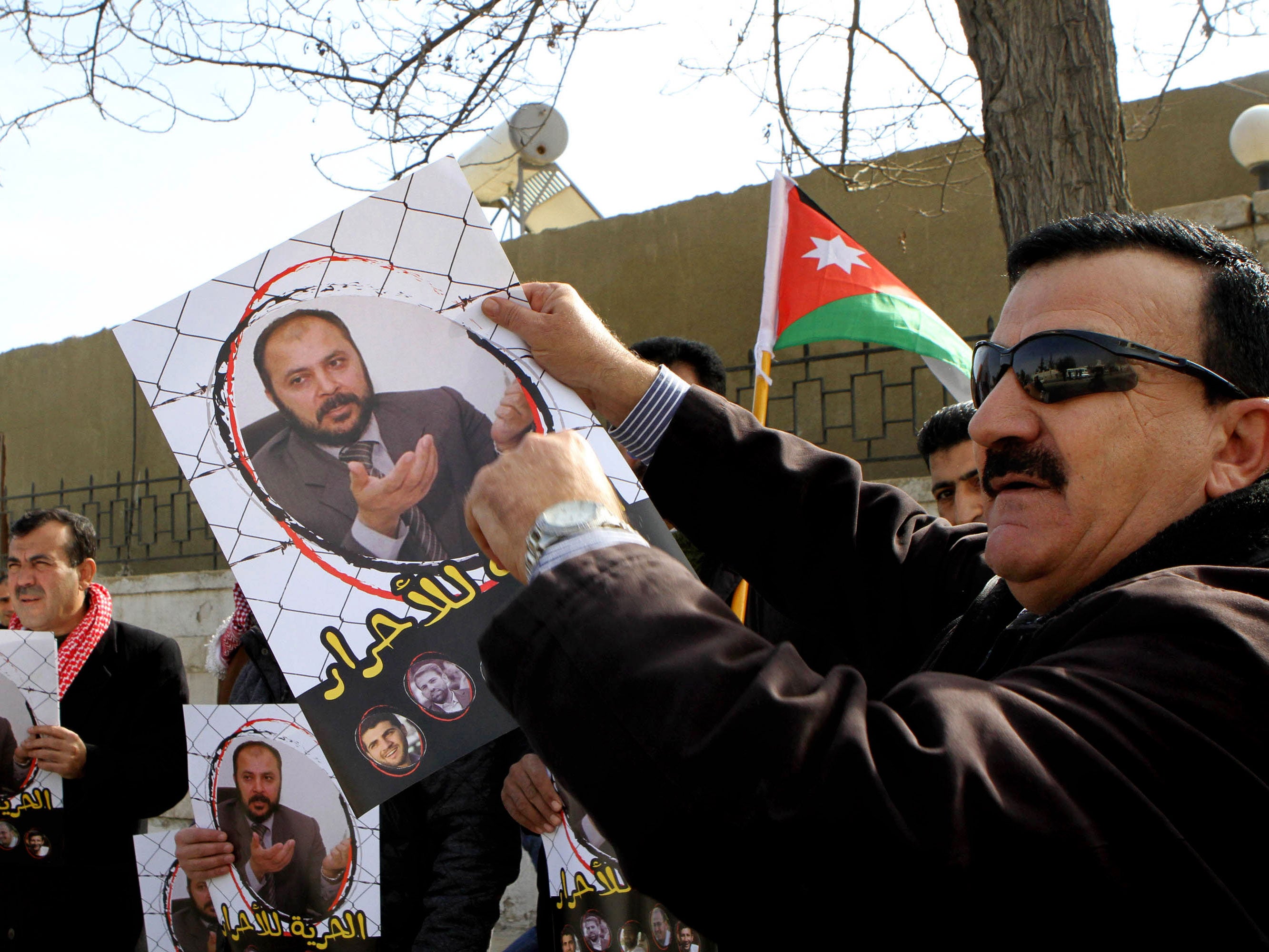 Supporters of Zaki Bani Ersheid, the number two in the Jordanian branch of the Brotherhood, hold photos of him, outside the state security court in Amman, Jordan