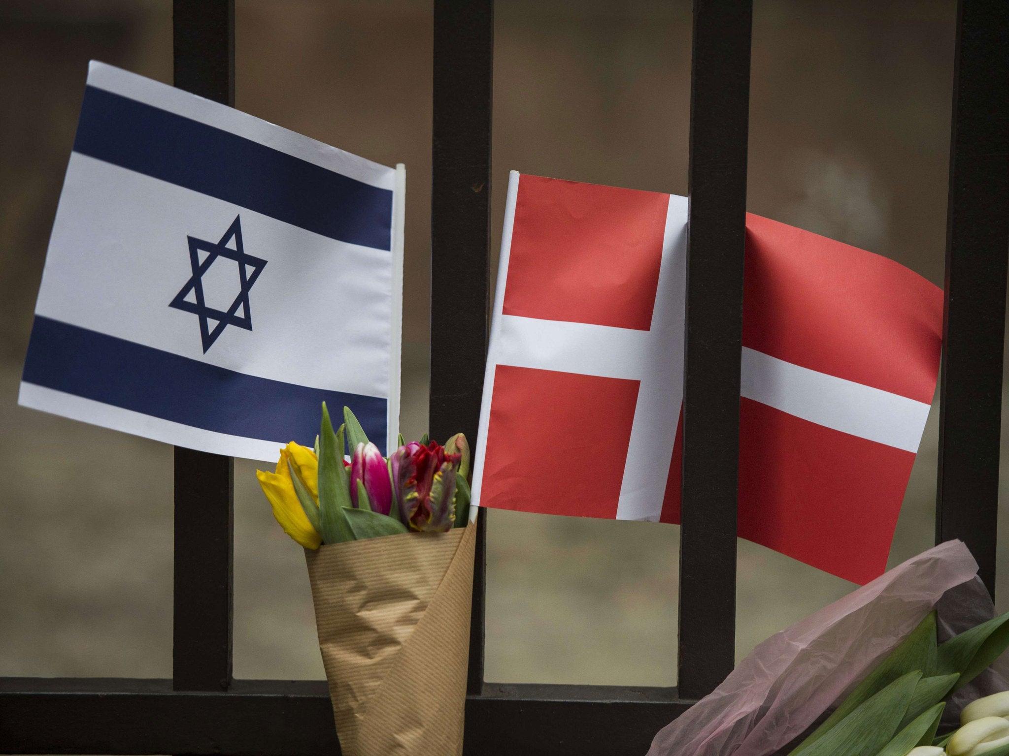 A Danish and an Israeli flag are seen among flowers and candles honouring the shooting victims outside the main Synagogue in Copenhagen