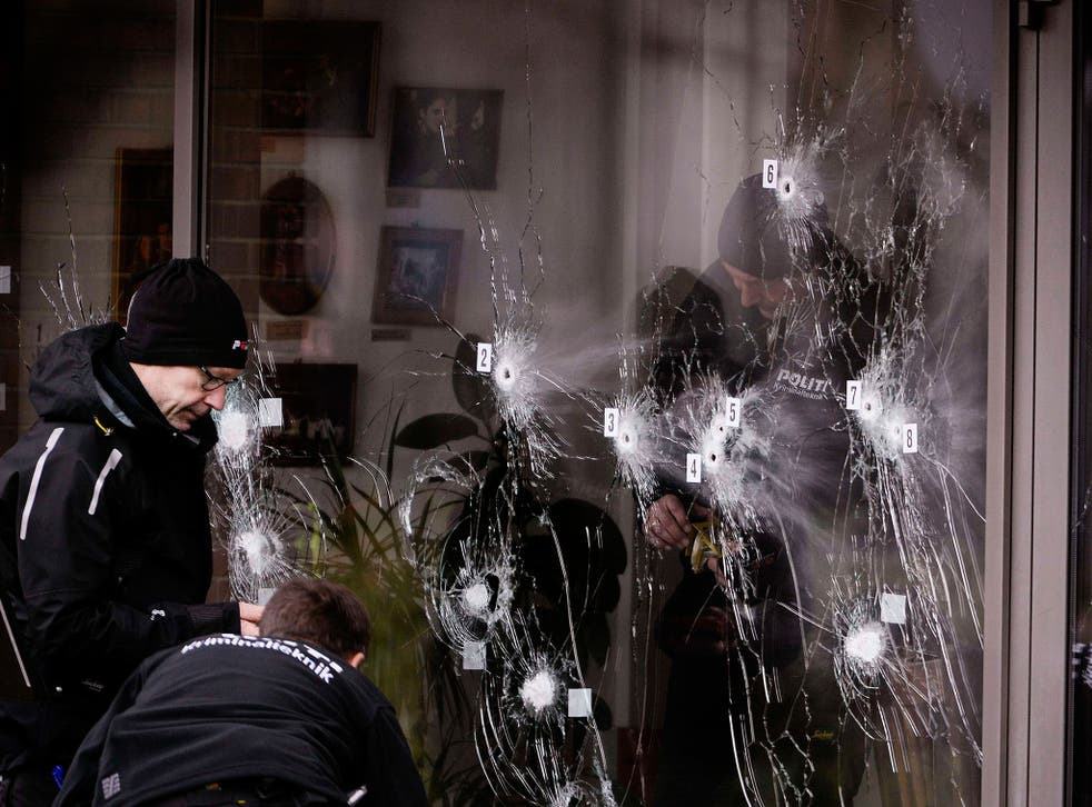 Police forensic technicians examine bullet holes in the door to Krudttønden café in Copenhagen