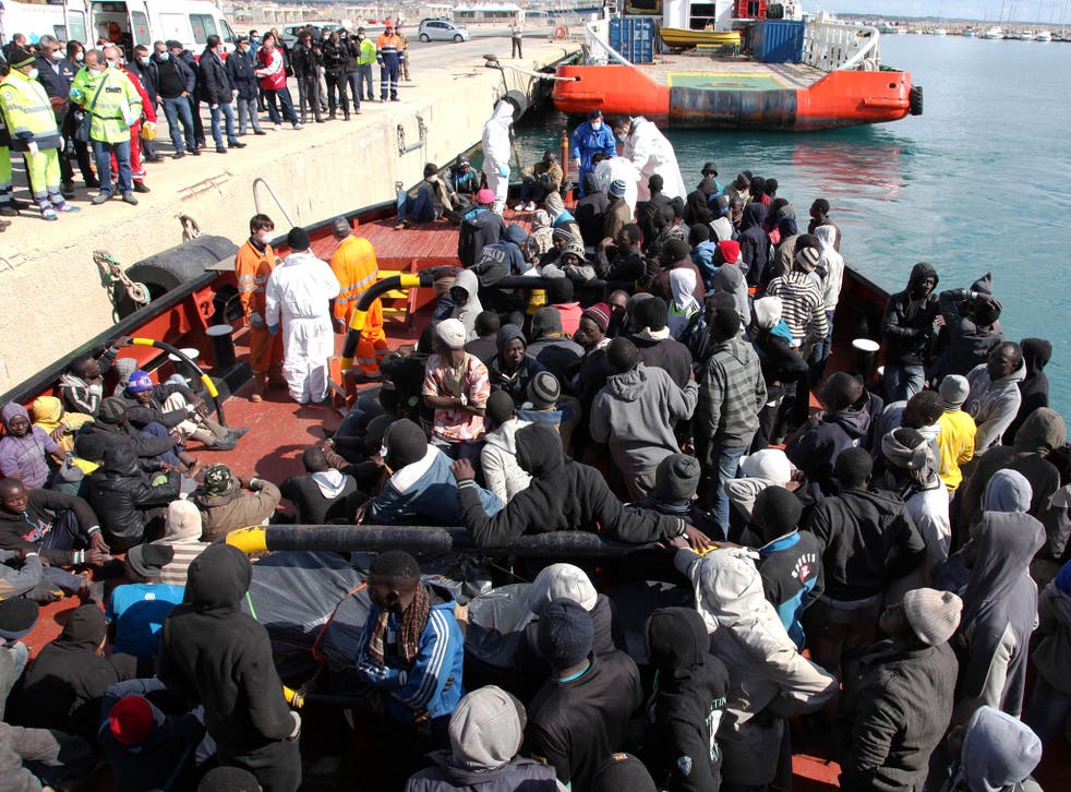 Migrants wait to disembark from a tug boat after being rescued in the Pozzallo harbor, Sicily, Italy