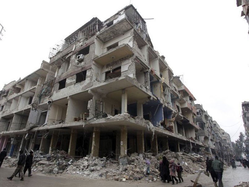 Residents walk past a damaged building in the Douma neighbourhood of Damascus, February 12, 2015.