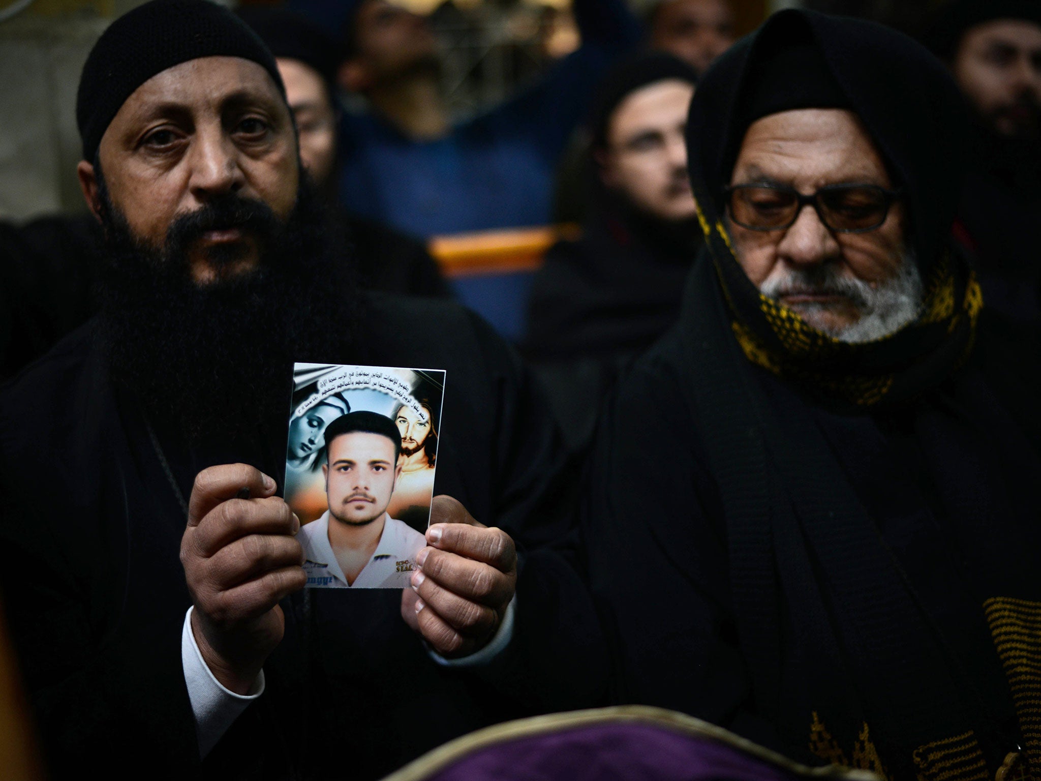 A Coptic clergyman shows a picture depicting one of the Coptic Christians murdered by Isis militants