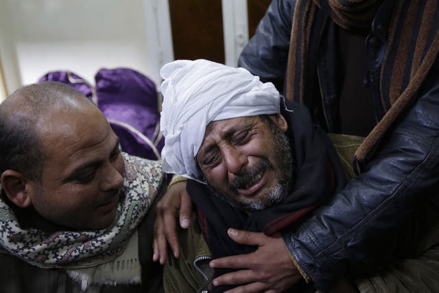 A man is comforted by others as he mourns over Egyptian Coptic Christians captured in Libya and killed by Isis-affiliated militants, on 16 February