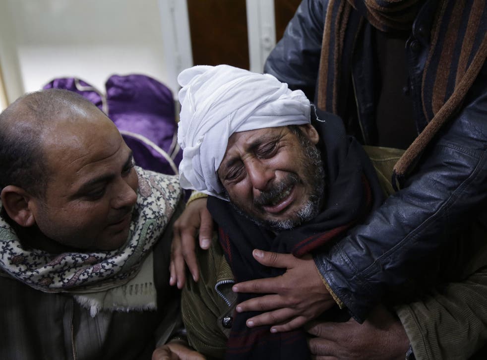 A man is comforted by others as he mourns over Egyptian Coptic Christians captured in Libya and killed by Isis-affiliated militants, on 16 February