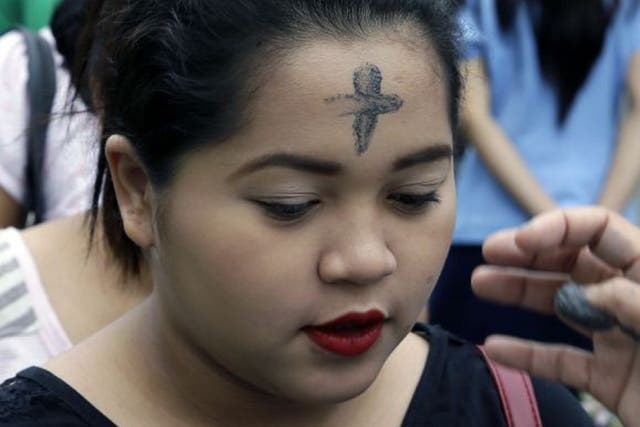 A woman has her head marked with a paste made from ashes on Ash Wednesday in the Philippines
