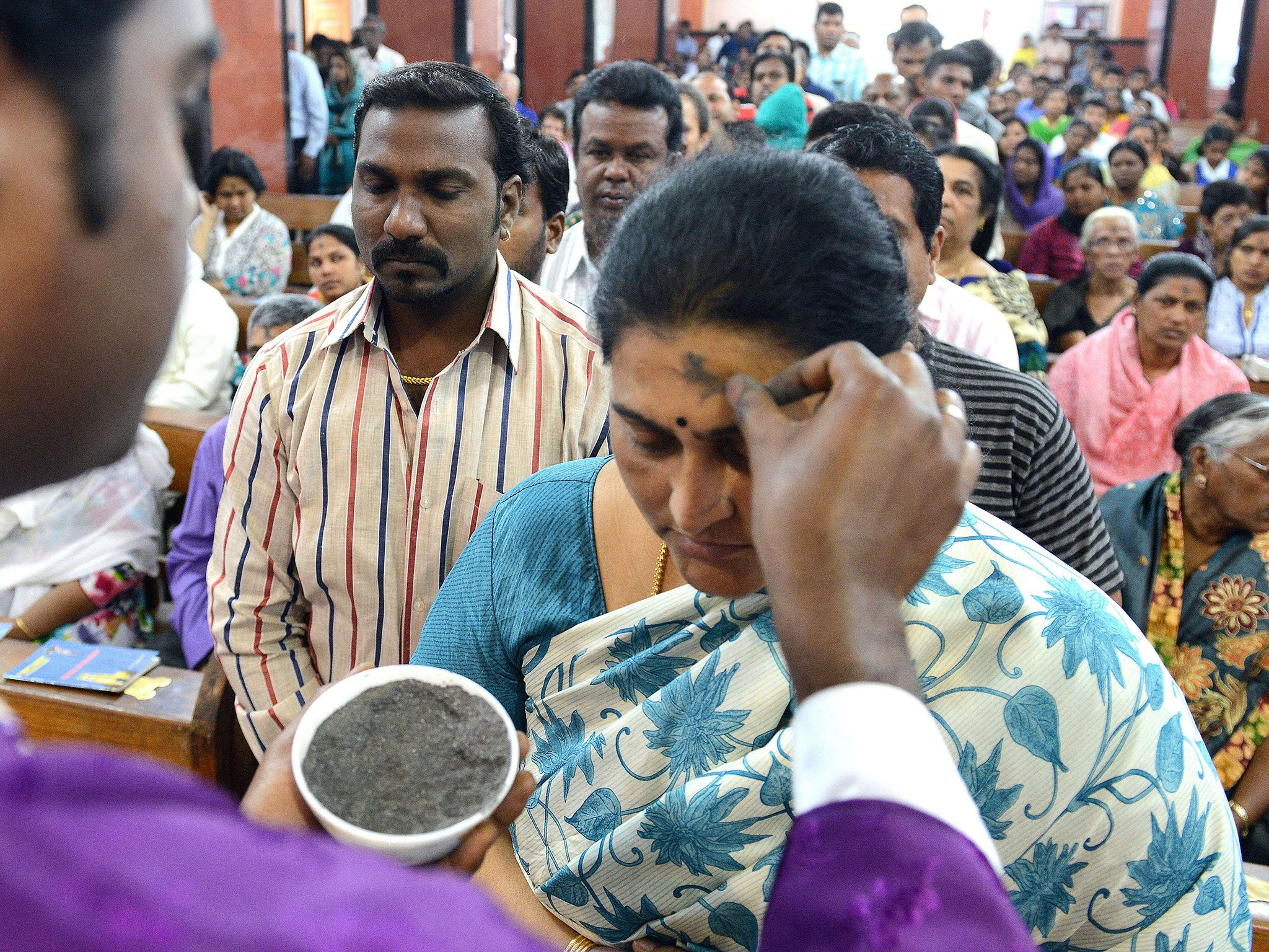 An Indian Catholic priest (L) marks the symbol of the cross with ash on the forehead of a Christian devotee during an Ash Wednesday service at Saint Mary's Basilica in Secunderabad, the twin city of Hyderabad, India