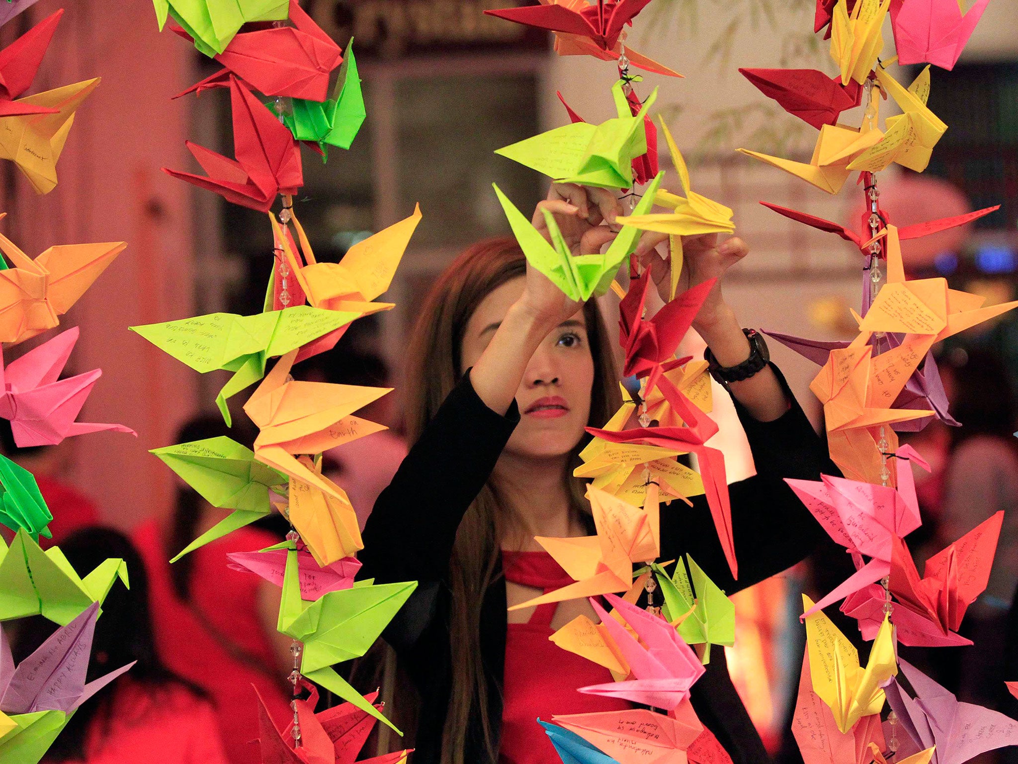 A woman hangs a paper crane with her wish written on it during Chinese New Year eve celebrations at Chinatown in Manila, Philippines