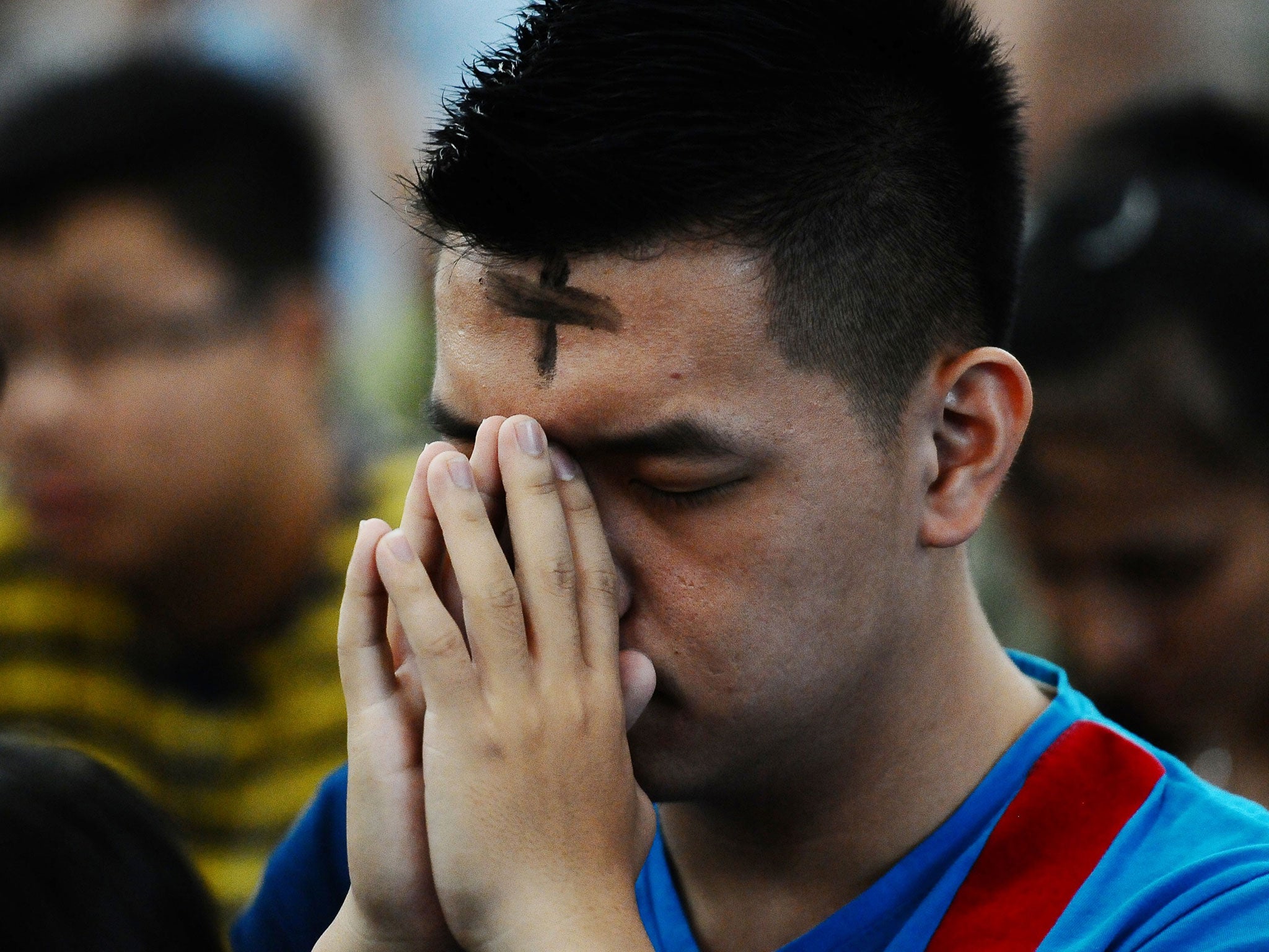 A Catholic man prays during the Ash Wednesday ceremony at Roh Kudus Church on March 5, 2014 in Surabaya, Indonesia.