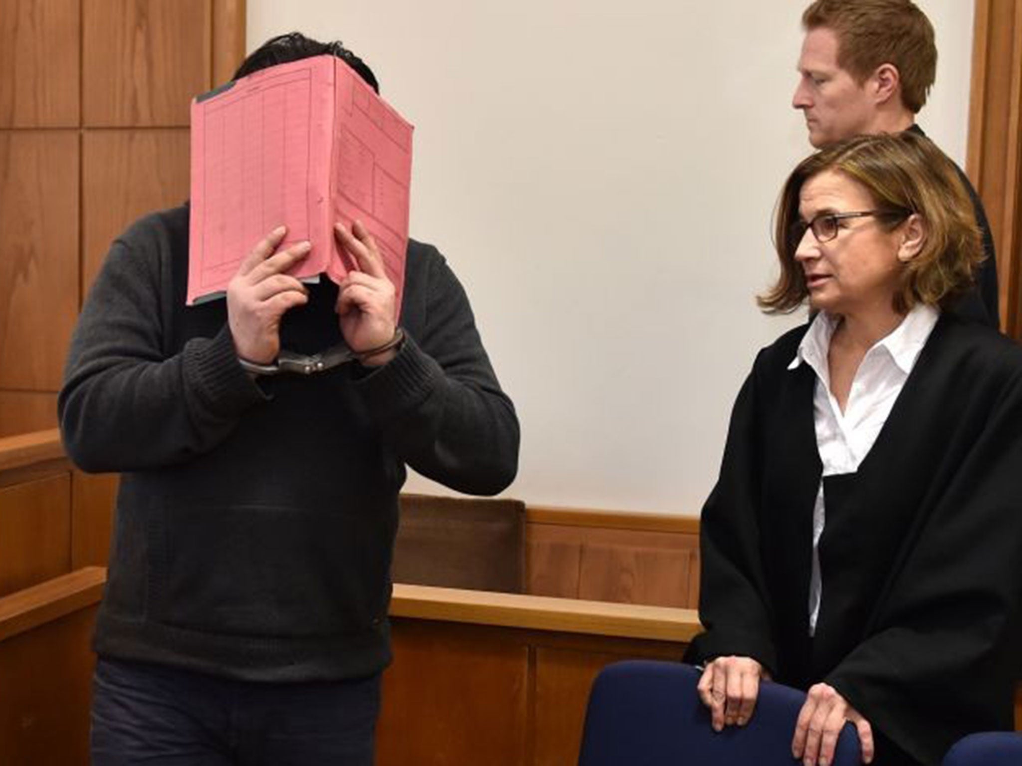 Former nurse, only identified as Niels H. hides his face behind a folder when arriving in the courtroom besides his lawyer Ulrike Baumann