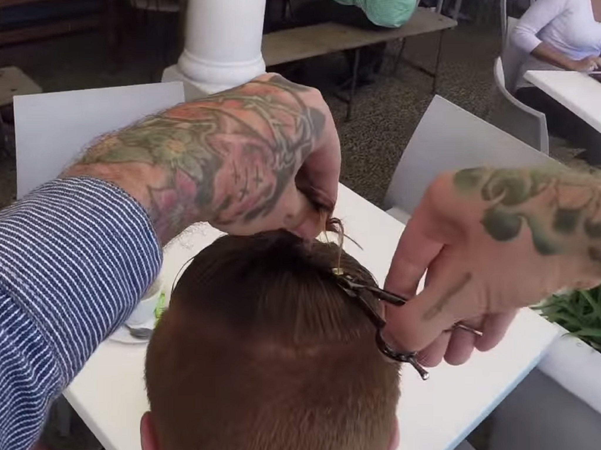A man gets his hair chopped off by a self-styled 'drive-by barber'
