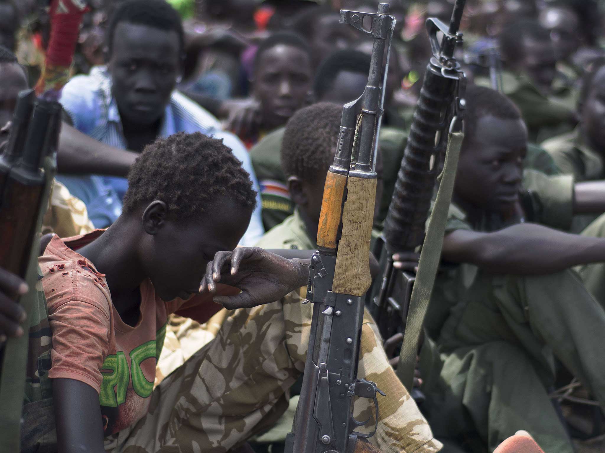 Child soldiers sit on 10 February with their rifles at a ceremony of the child soldiers disarmament, demobilisation and reintegration