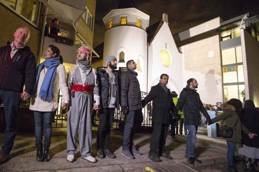 Muslims join hands to form a human shield as they stand outside a synagogue in Oslo