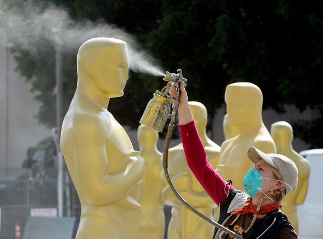 Dena D'Angelo spray paints an Oscar statue with gold during preparation of 87th Annual Academy Awards at Dolby Theater 