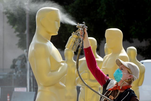 Dena D'Angelo spray paints an Oscar statue with gold during preparation of 87th Annual Academy Awards at Dolby Theater 
