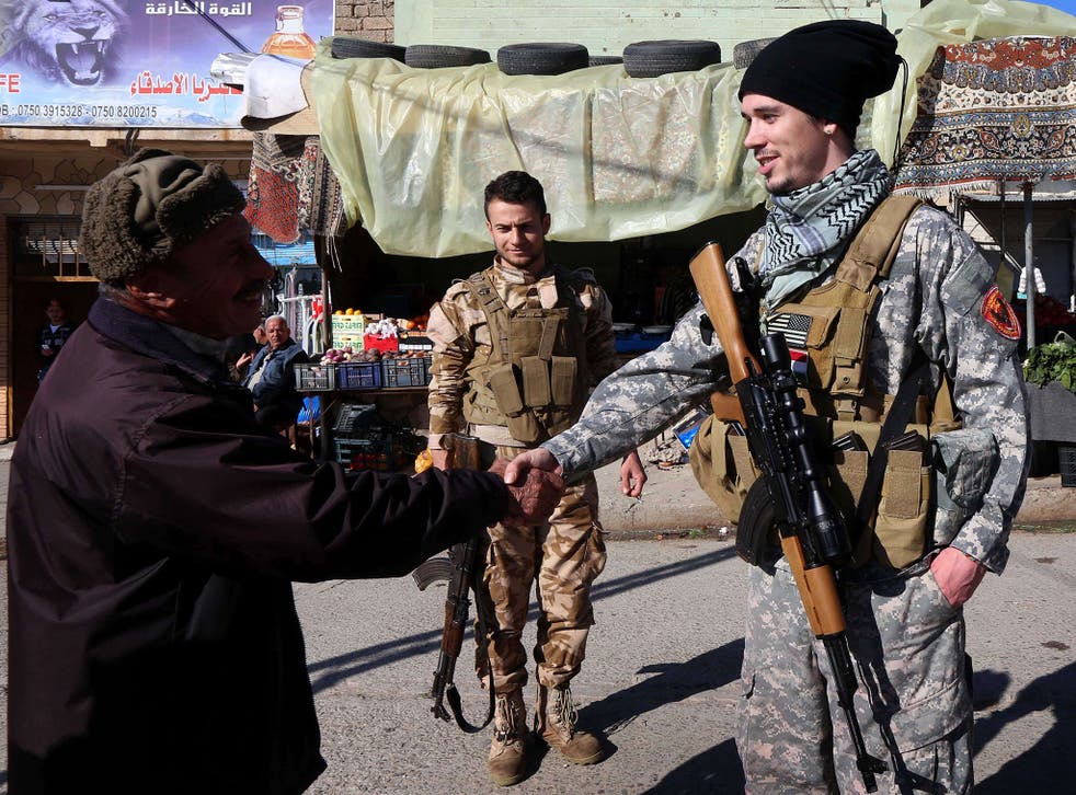 Brett, right, a 28-year-old American fighting Isis as part of Dwekh Nawsha, a Assyrian Christian militia, meets a passer-by in Al-Qosh, 20 miles north of Mosul