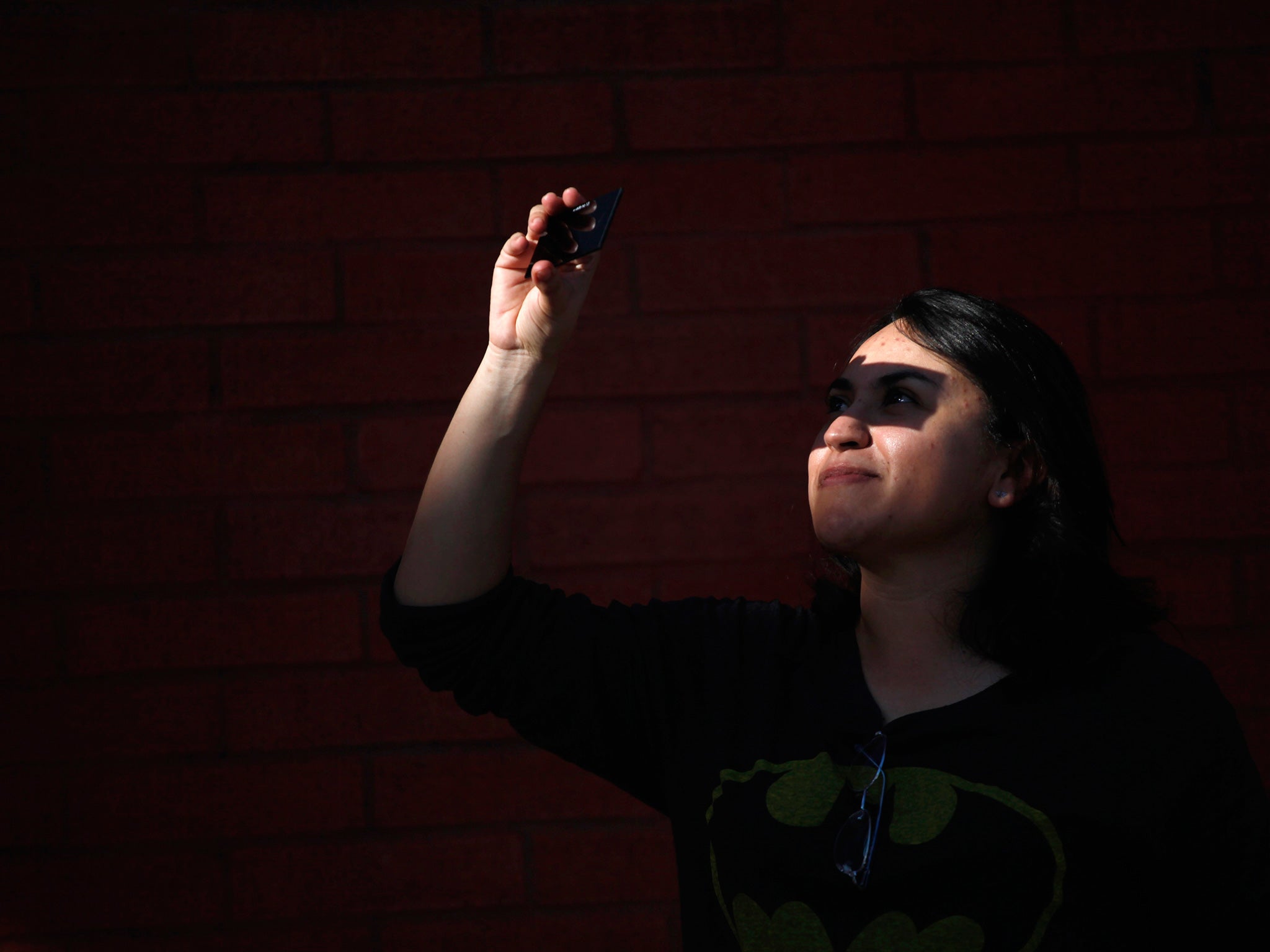 A woman looks up to view a partial solar eclipse outside the La Rodadora Museum in Ciudad Juarez, October 23, 2014