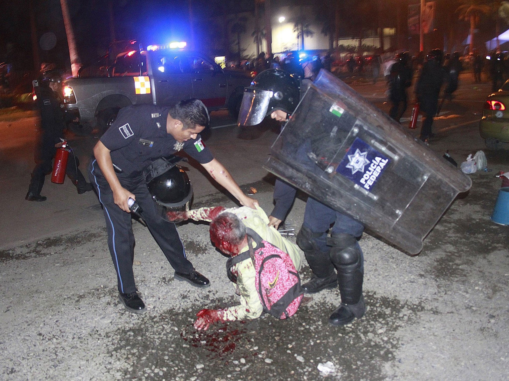 Federal policemen detain an injured teacher after demonstrators blocked the main access to the airport in Acapulco on 24 February, 2015