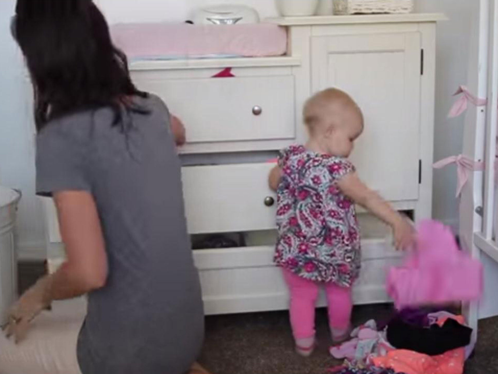 A baby 'helps' its mother by pulling all of the clothes out of the drawer